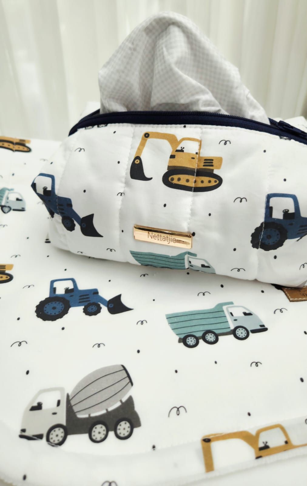 A quilted tissue box cover and matching fabric featuring colorful construction vehicles including trucks and excavators on white.