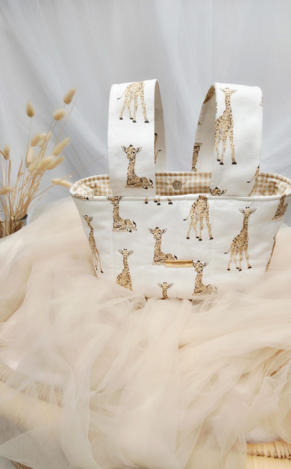 Handmade white fabric tote bag with cute giraffe print pattern and gingham lining, perfect for baby shower gifts.
