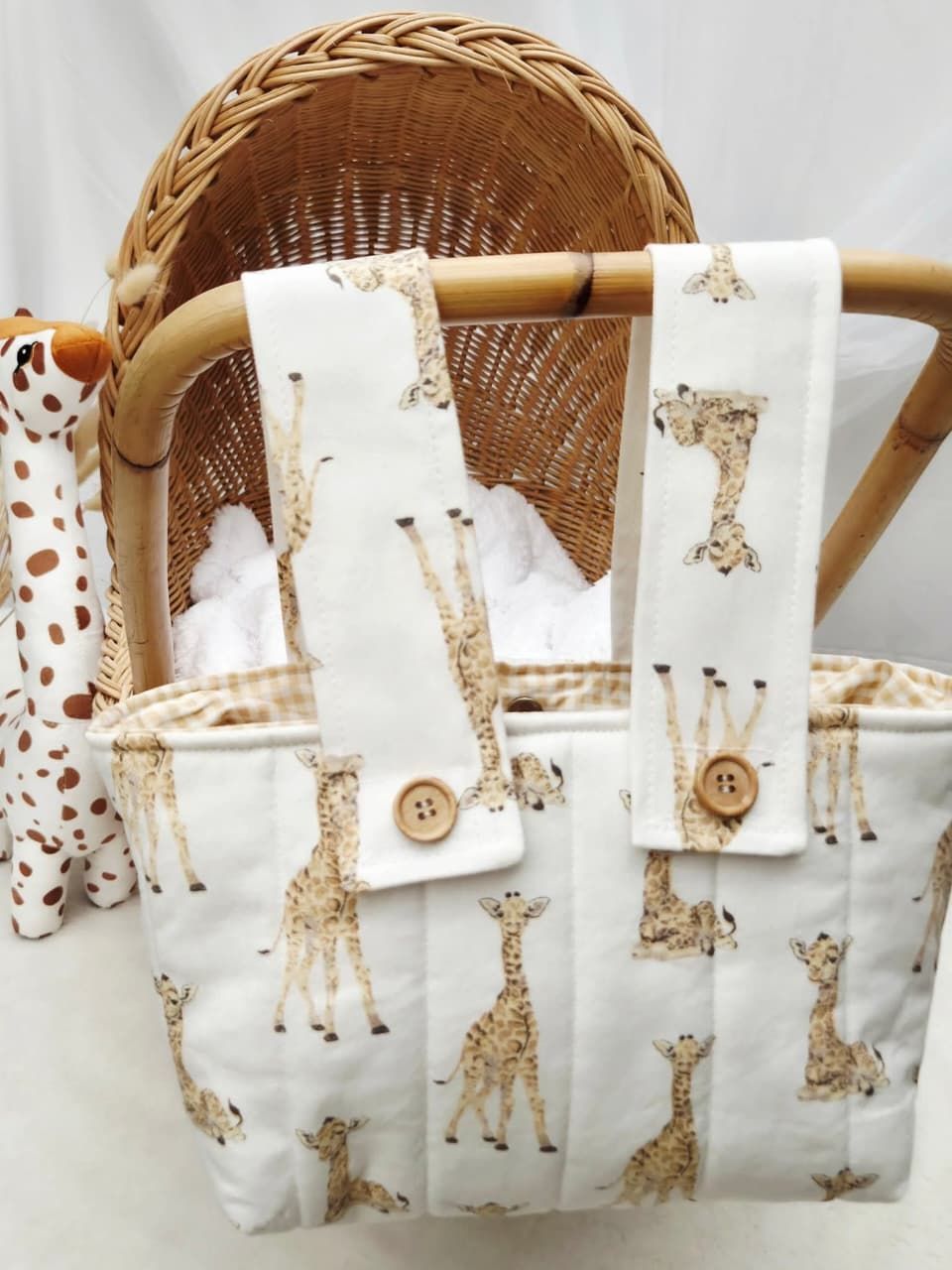 White fabric tote bag and matching strap featuring cute giraffe print pattern with wooden button closure, displayed in wicker basket.
