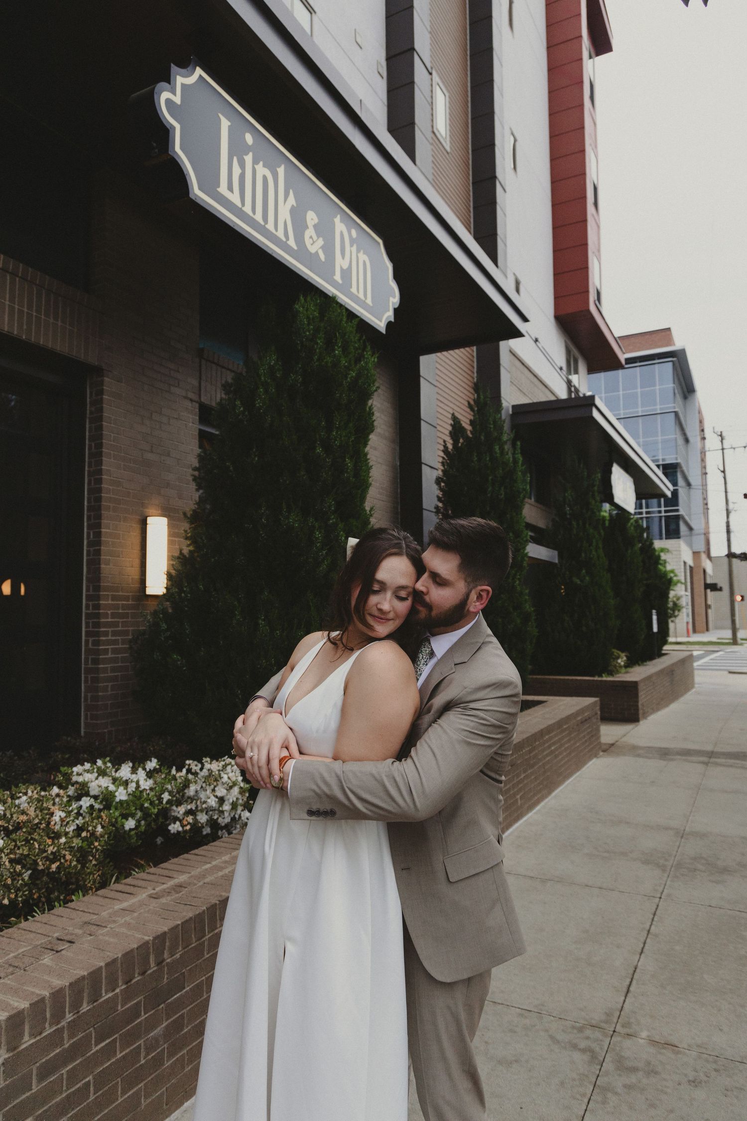 Romantic couple embracing outside Link & Main restaurant storefront.