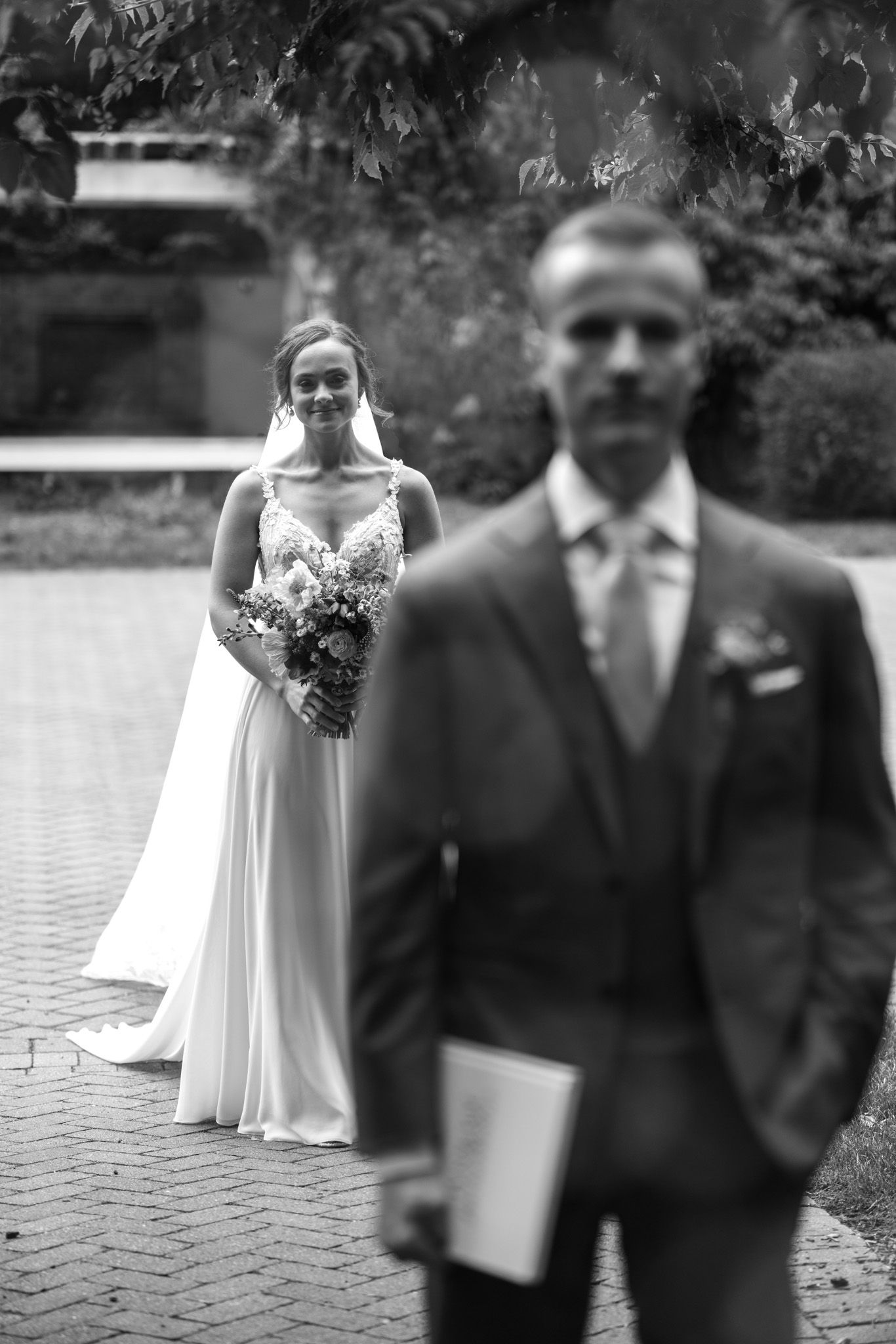 Black and white portrait of a bride standing behind groom during first look wedding moment.