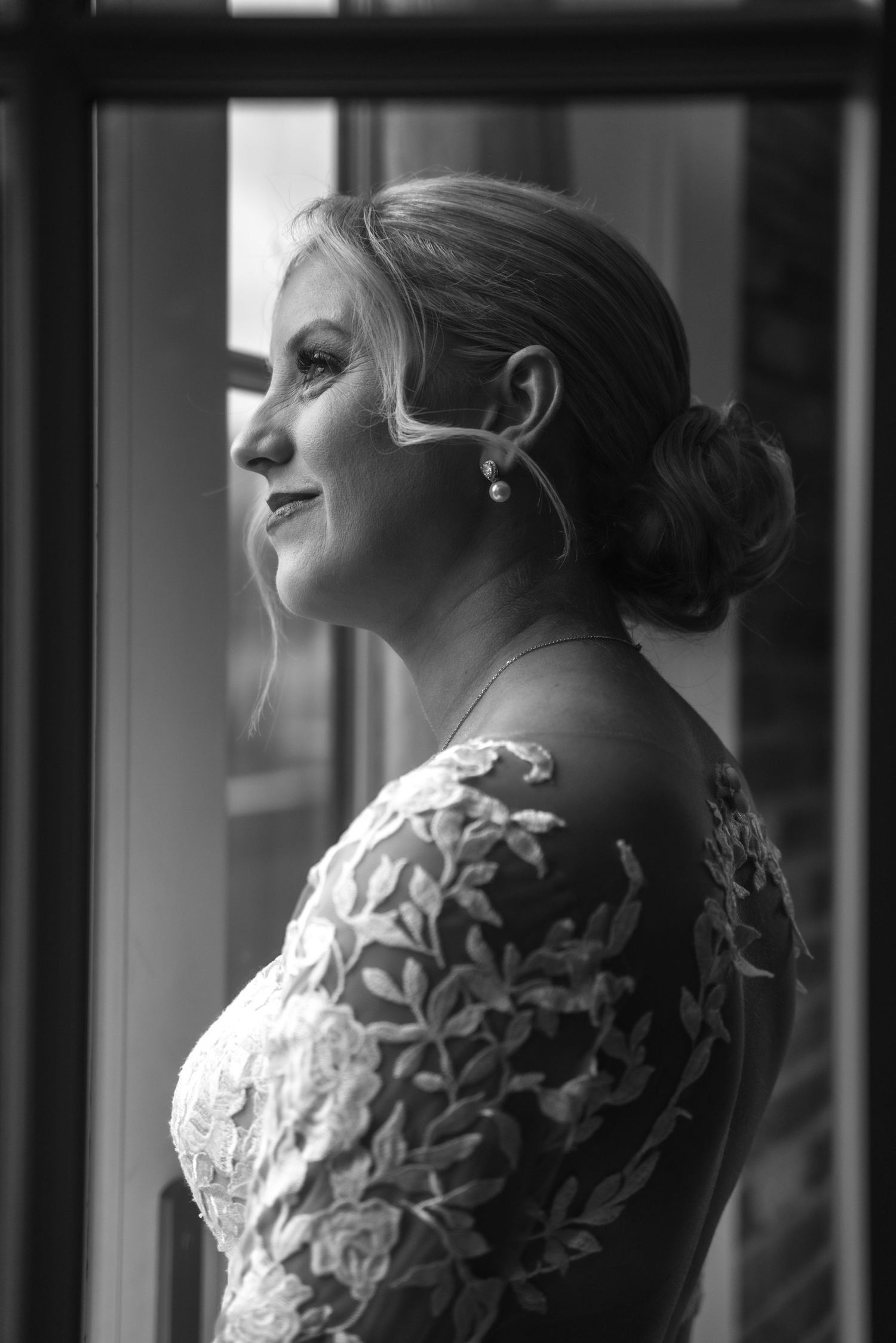 Black and white side profile of bride wearing intricate lace dress.