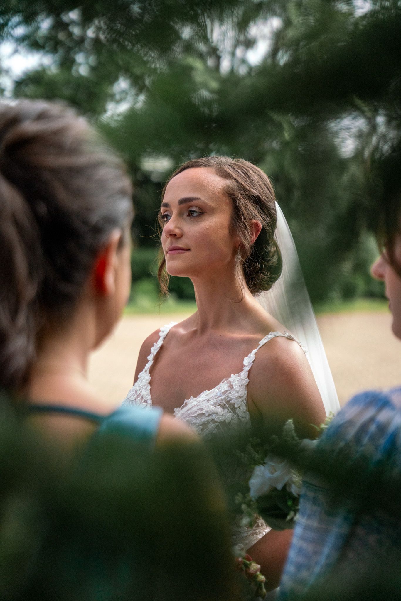 Elegant bride with classic updo and veil poses during outdoor wedding portraits.