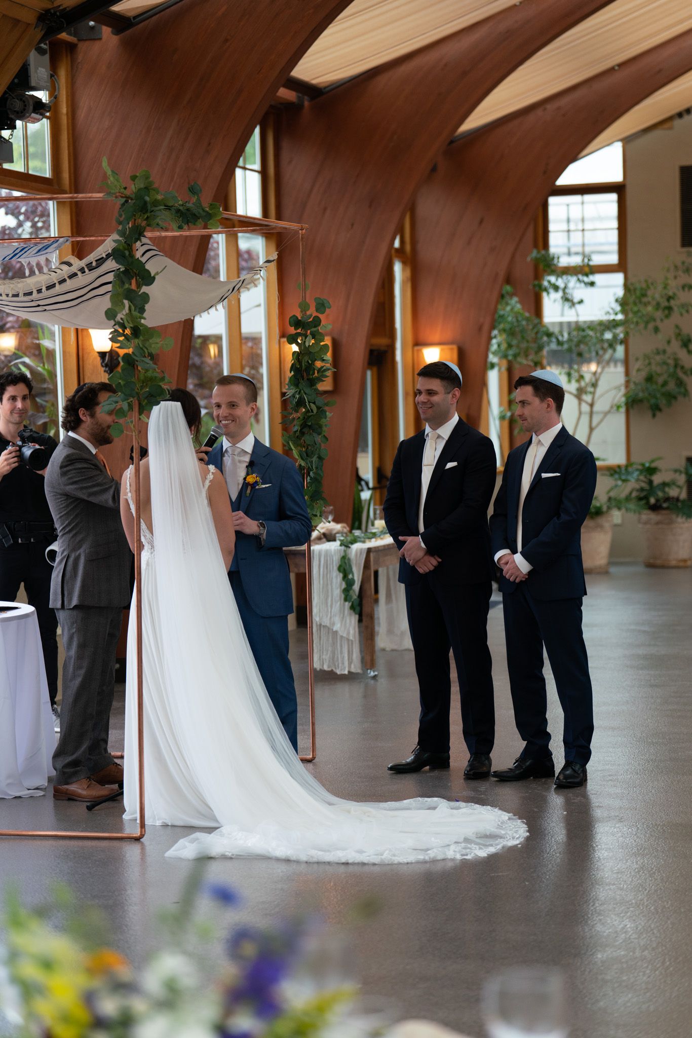 Wedding ceremony in elegant wood-beamed venue with floral decorations.