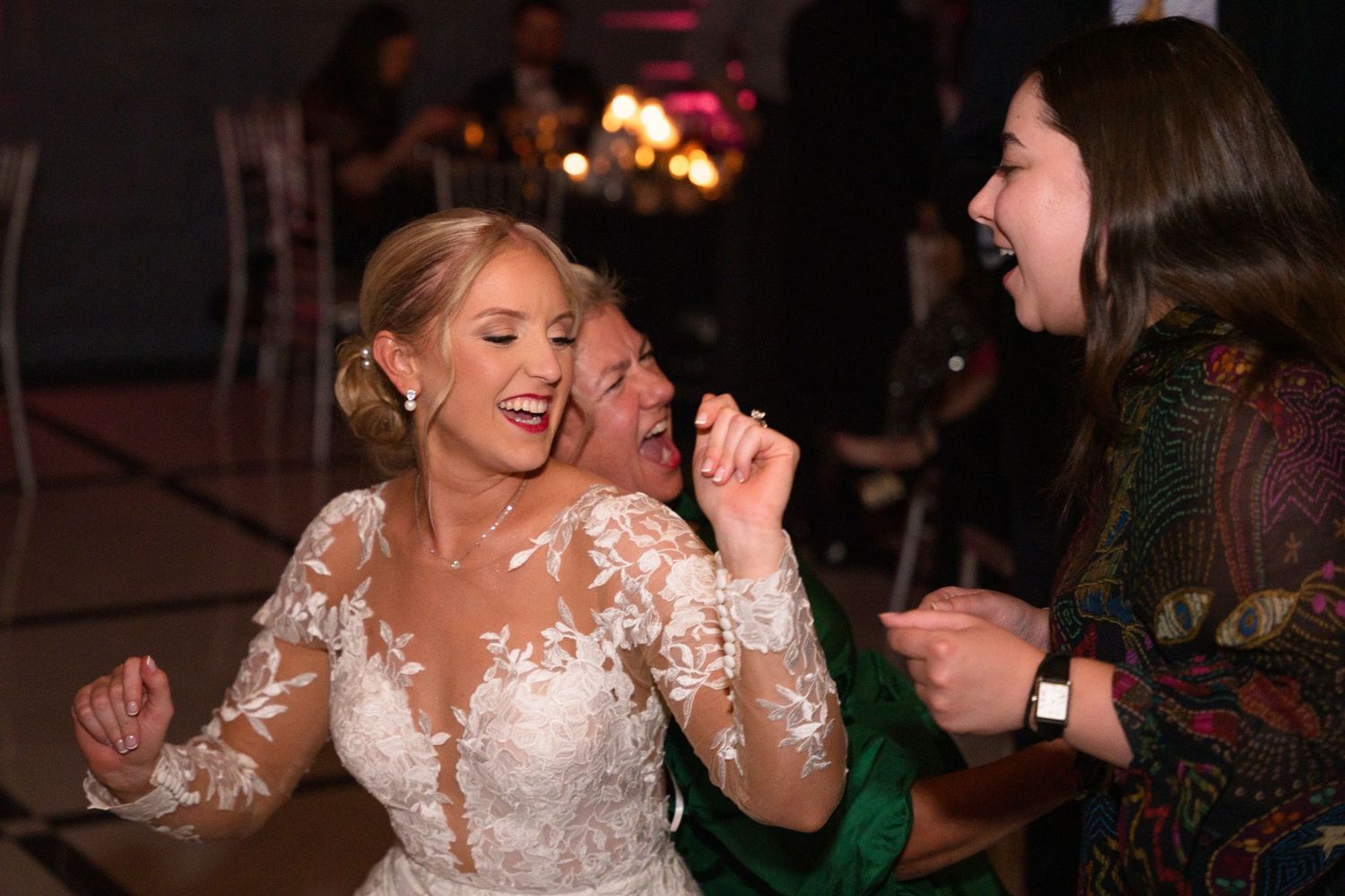 People dancing and singing together enthusiastically at a wedding reception.