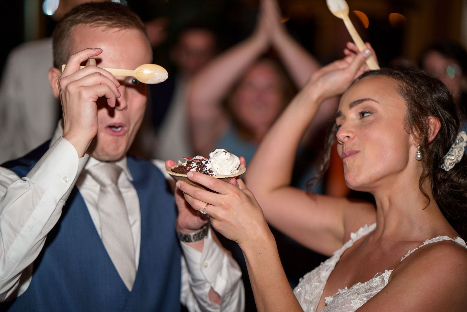 Newlywed couple playfully smash cake into each others faces during wedding reception celebration.