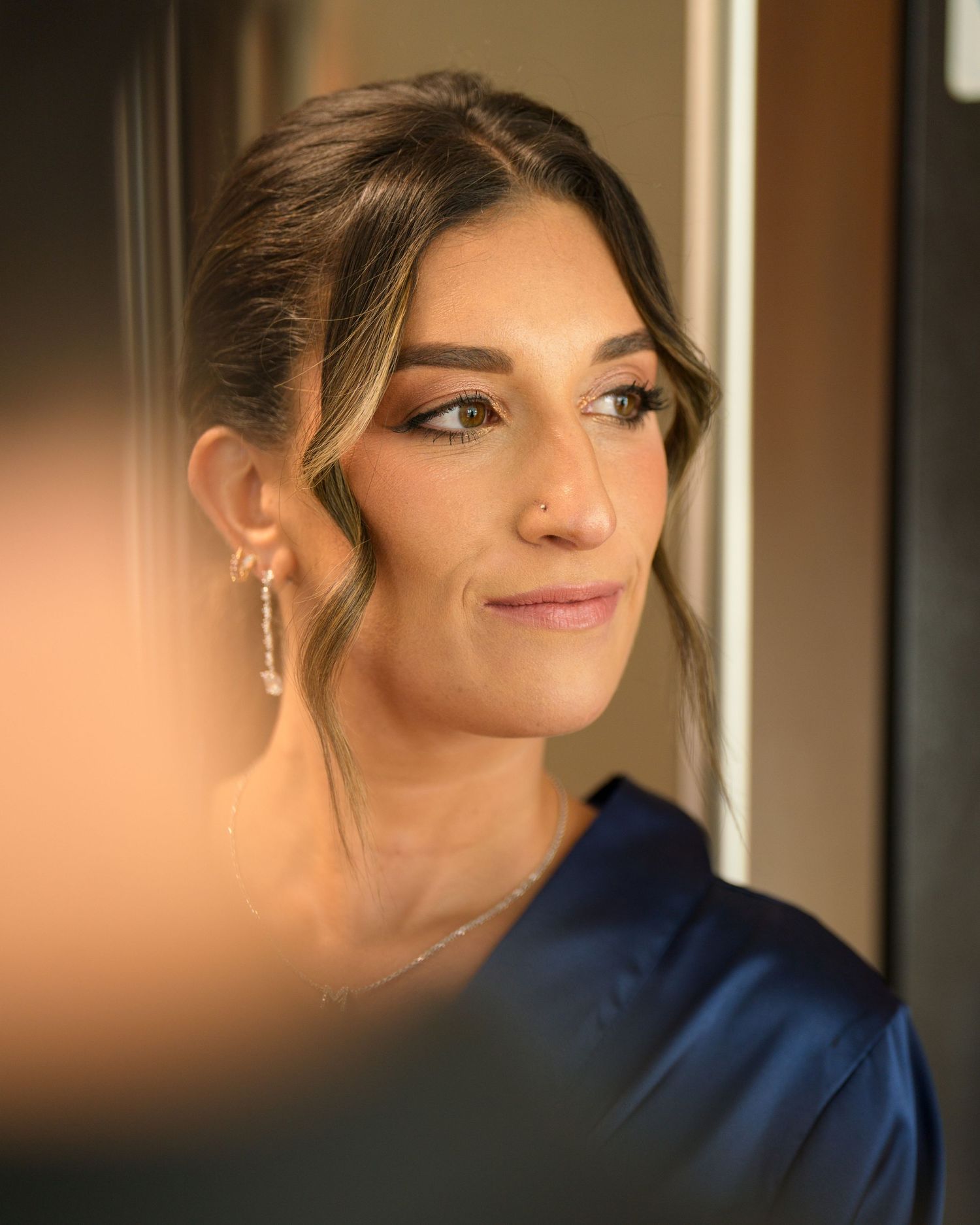 A portrait shows an elegant woman in a navy blue top, wearing dangling earrings and styled hair looking to the side.