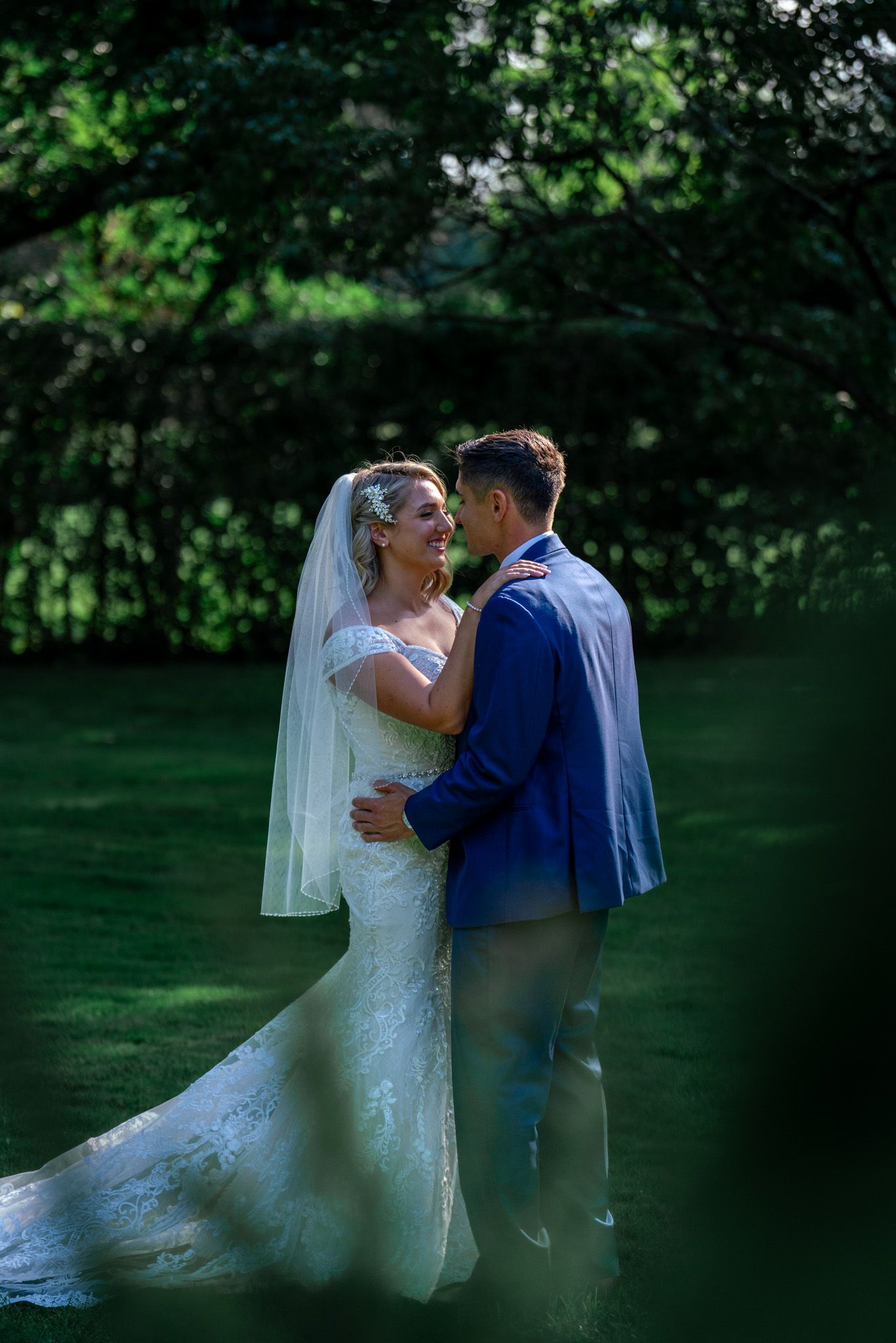 A romantic wedding moment captured in a lush garden setting with soft natural lighting and greenery in the background.
