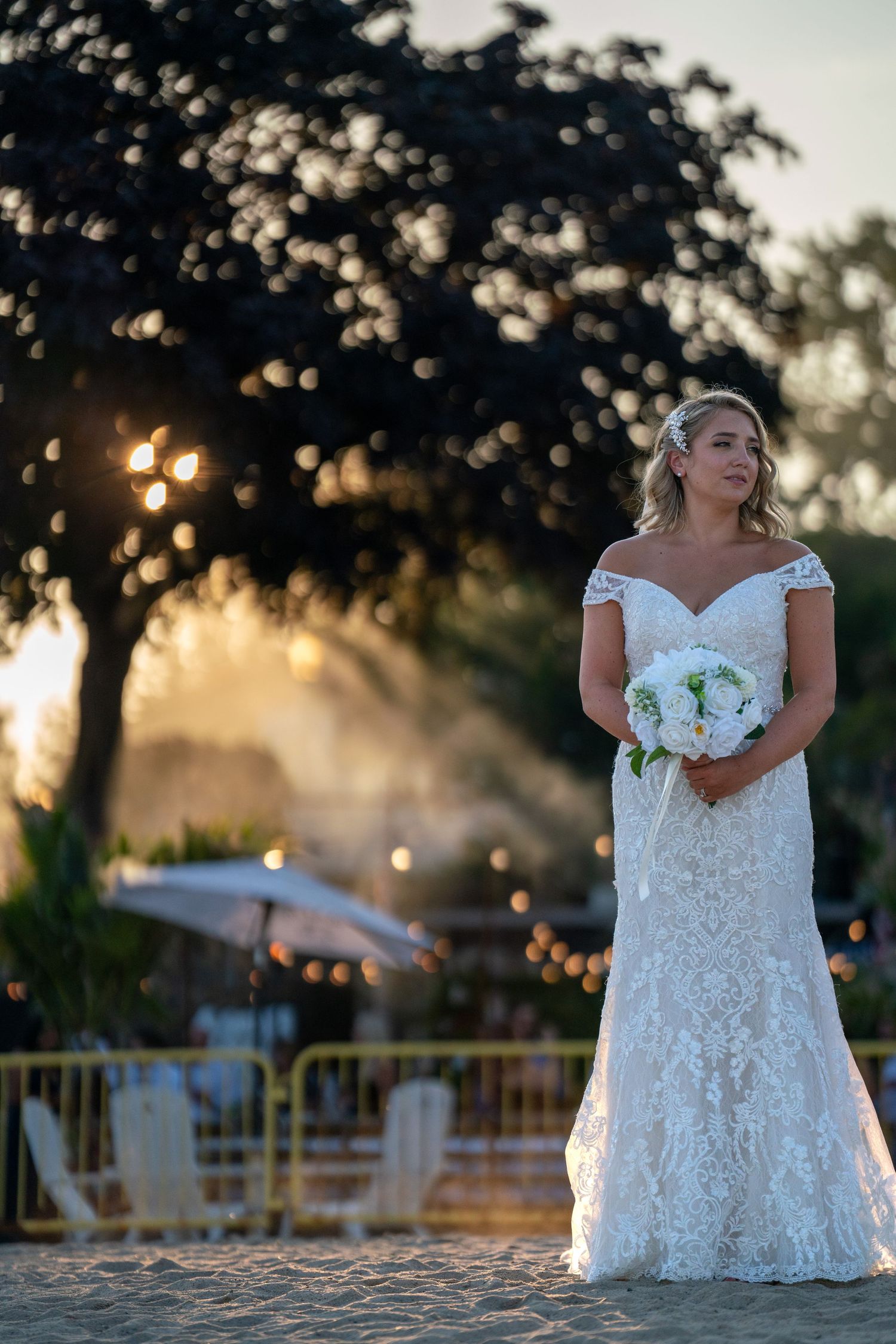 A sunset wedding portrait with string lights and trees creating a magical golden hour atmosphere.