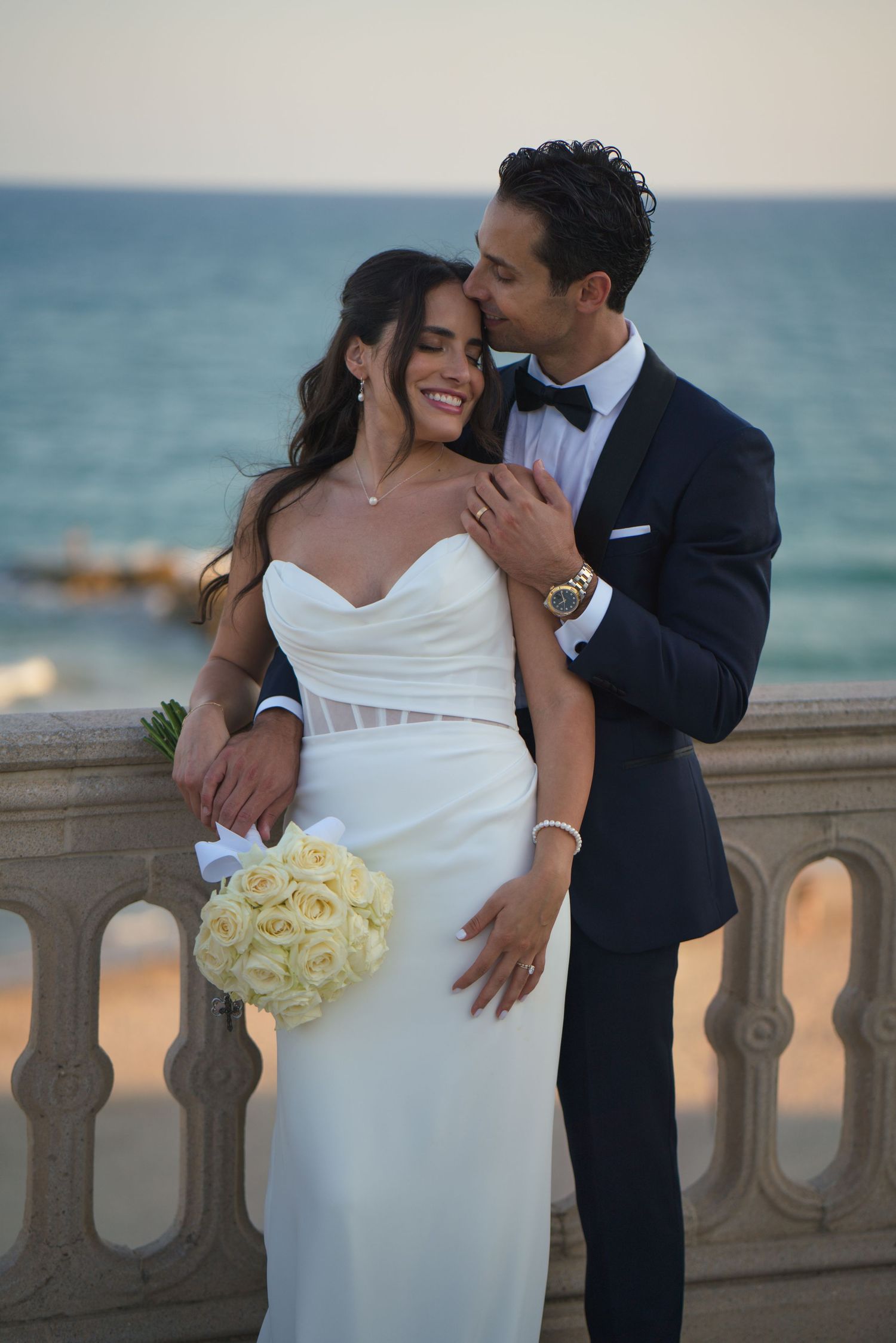 A romantic wedding moment captured on an oceanfront balcony with soft lighting.
