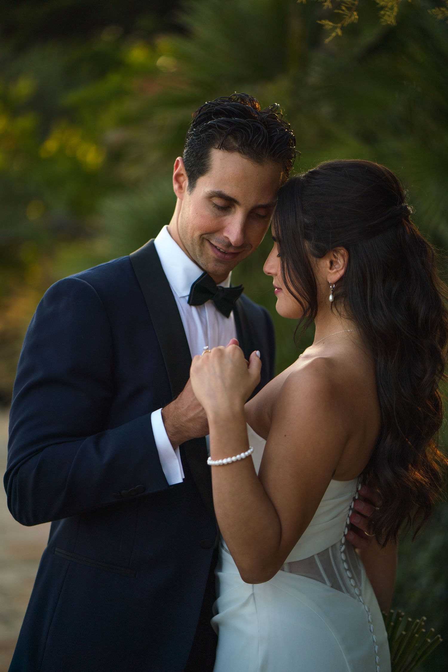 Tender moment between couple in formal attire during golden hour wedding photoshoot.