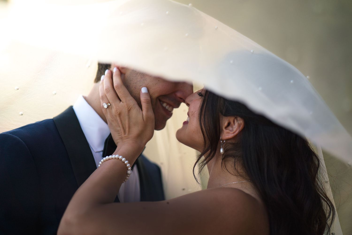 An intimate wedding moment captured through a white veil during sunset.