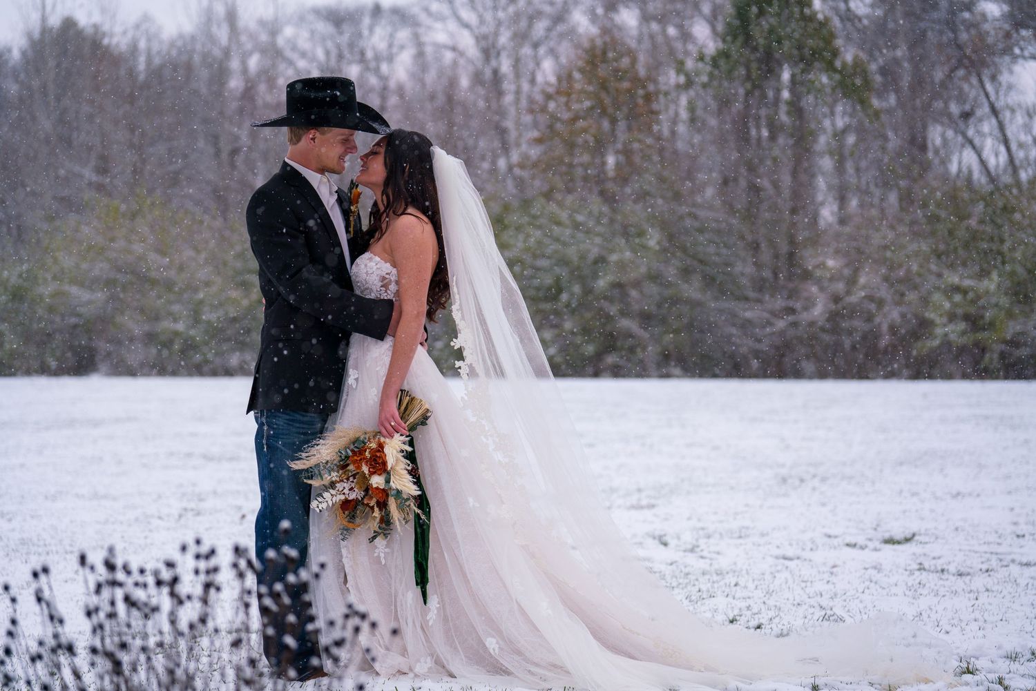 A romantic winter wedding scene with snow falling around the couple in formal attire.