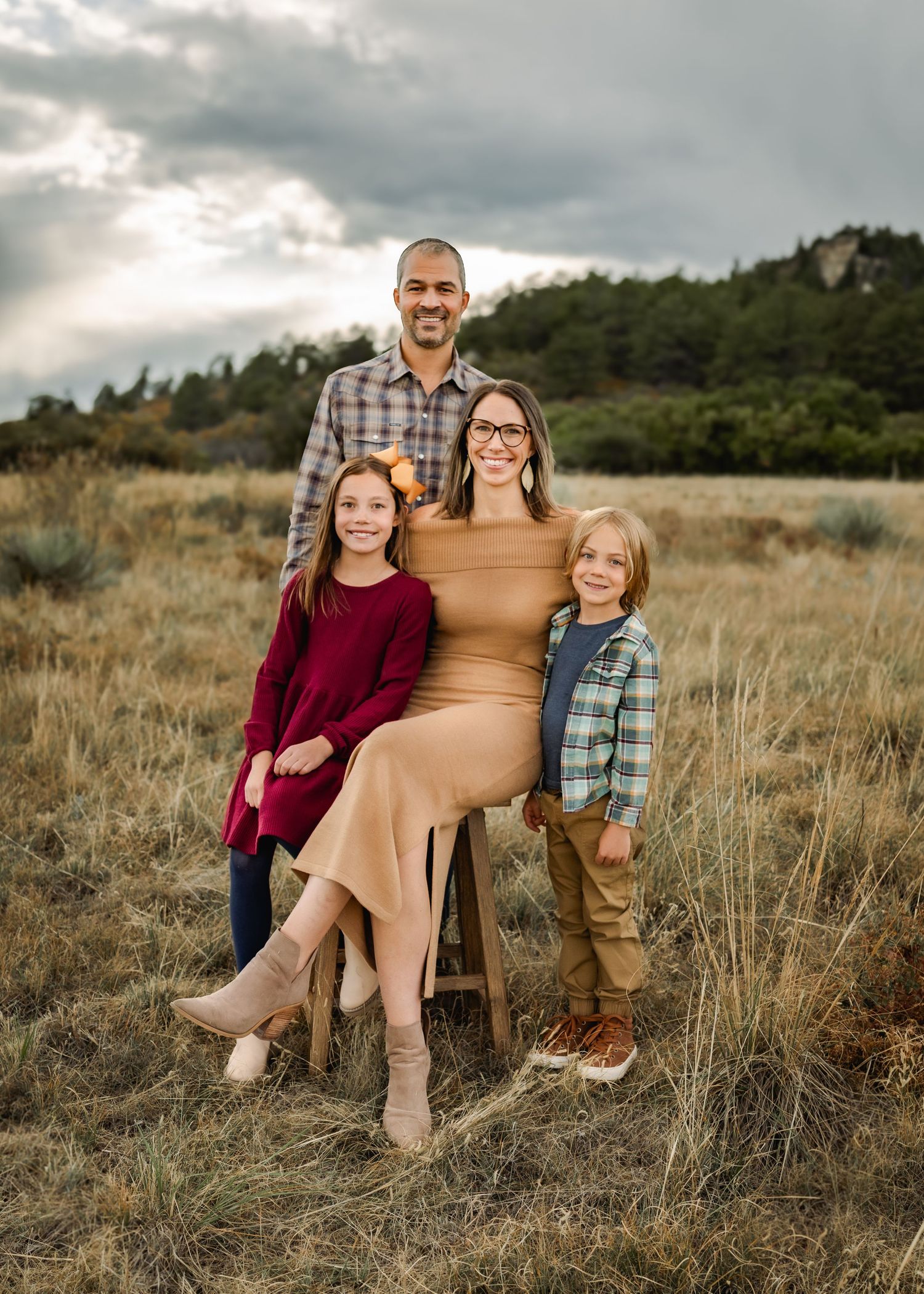 Family portrait session in casual fall attire against mountain landscape backdrop.