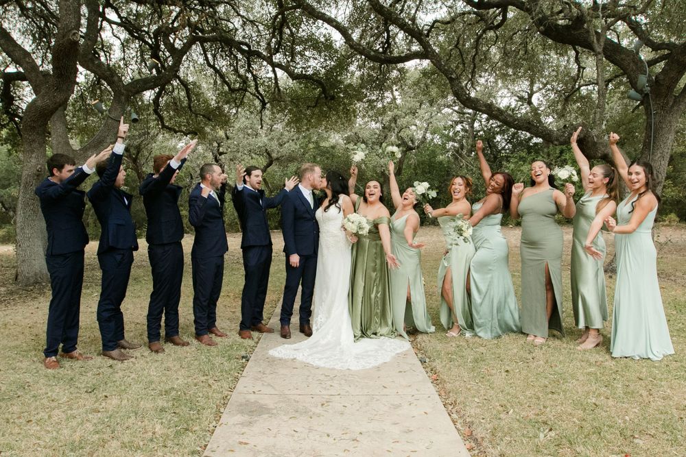 Wedding party poses outdoors with bridesmaids in light blue dresses.
