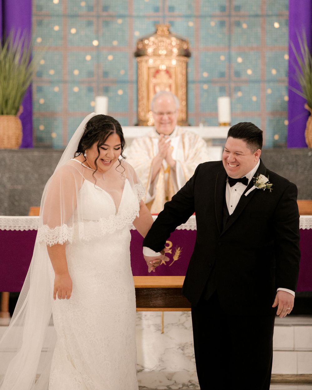 Joyful wedding ceremony moment in church with couple and officiant at altar.
