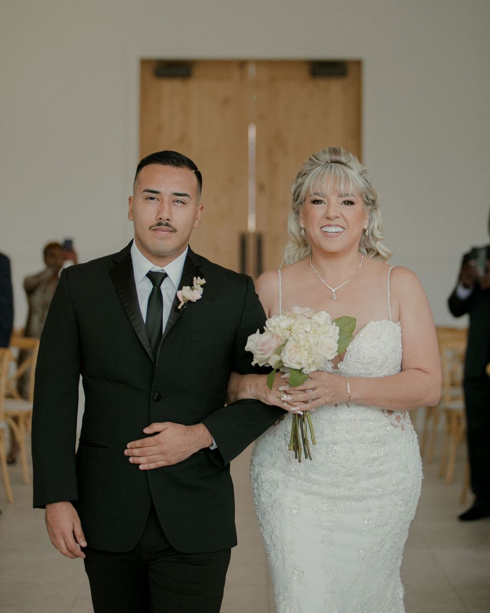 Wedding portrait of couple in formal attire against minimalist background.
