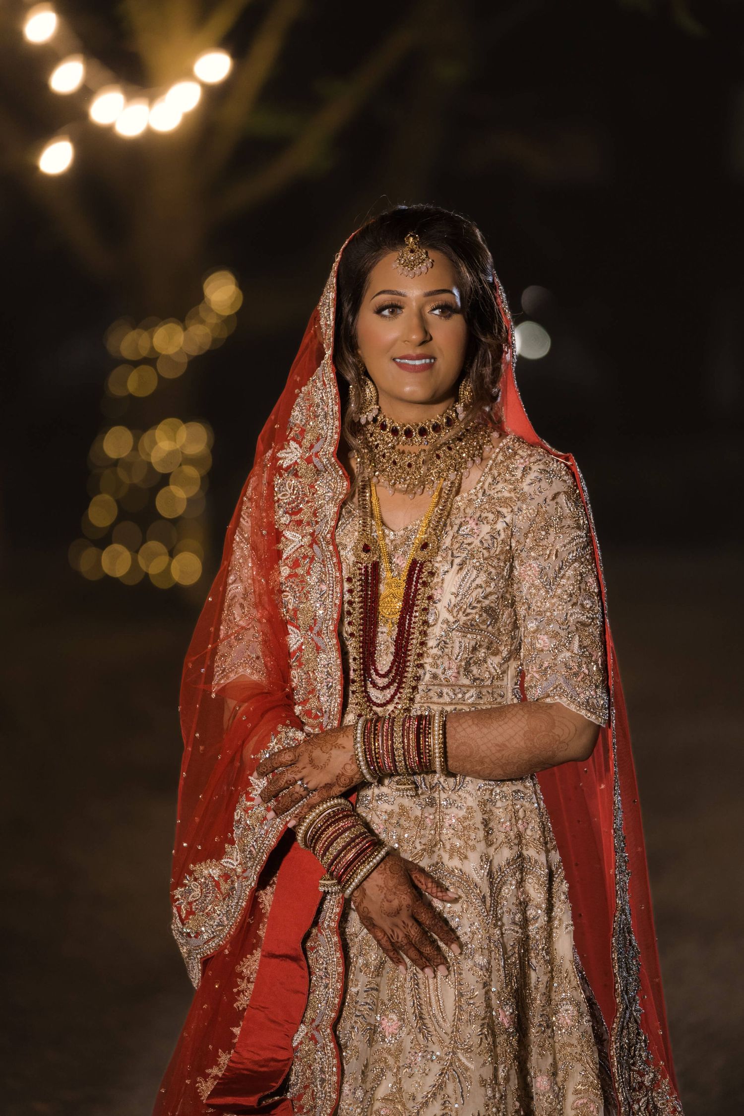 Young Indian bride posing in front of bright lights awaiting her sangeet ceremony.