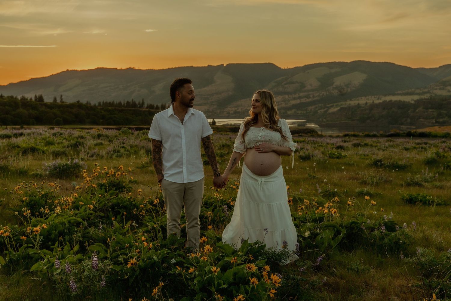 A romantic couple embraces near a misty lake at dusk with moody storm clouds overhead. PNW Couples photographer