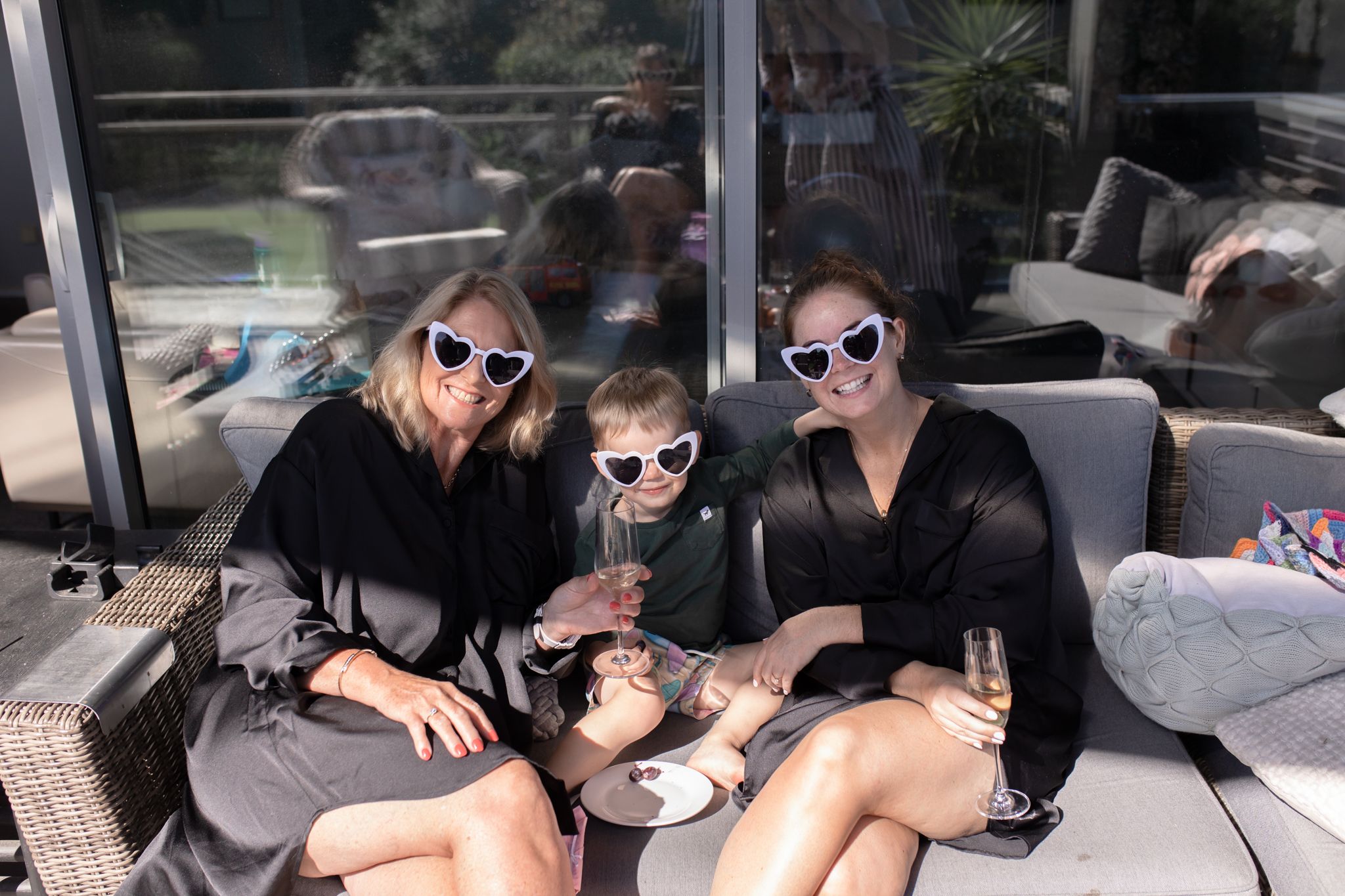 Three friends in black robes wearing sunglasses relaxing outdoors.