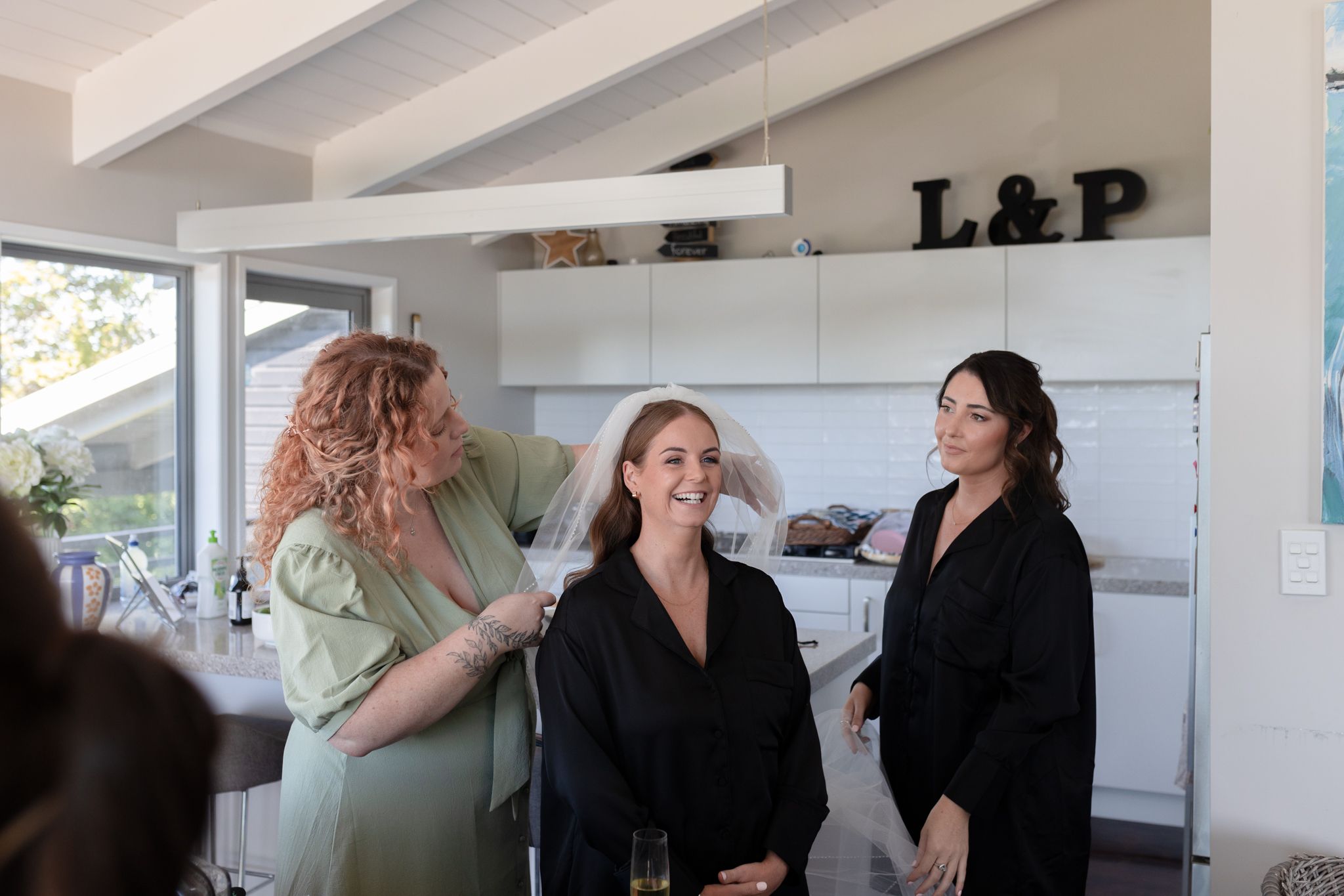 Wedding preparation scene showing styling and makeup being done in a bright room.