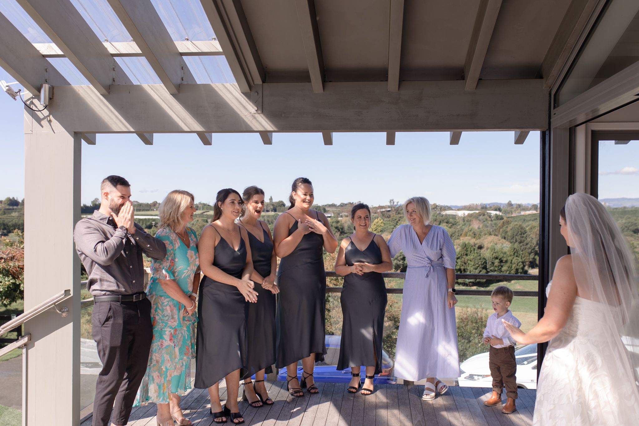 Wedding party gathered on a sunny balcony for a special moment with the bride.