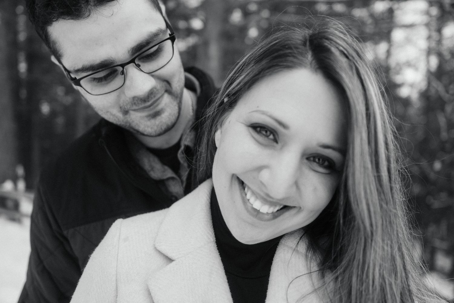 A couple shares a tender black and white portrait moment outdoors.