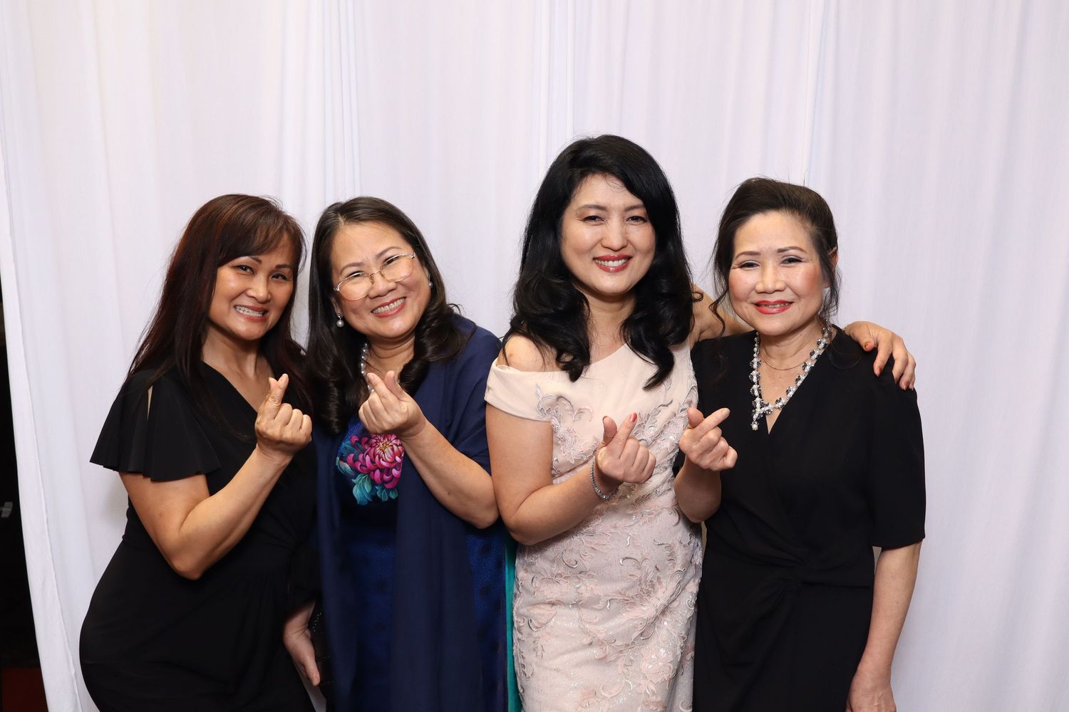Four women in formal attire pose together for a celebratory photo.