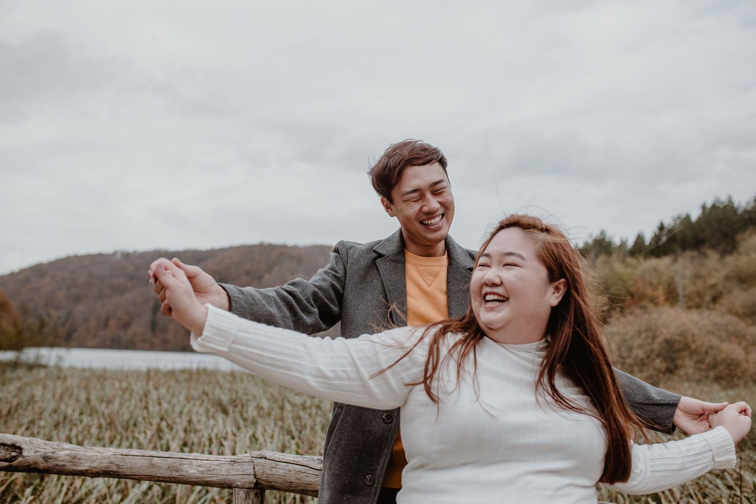 A couple sharing a playful moment outdoors against a mountain backdrop.