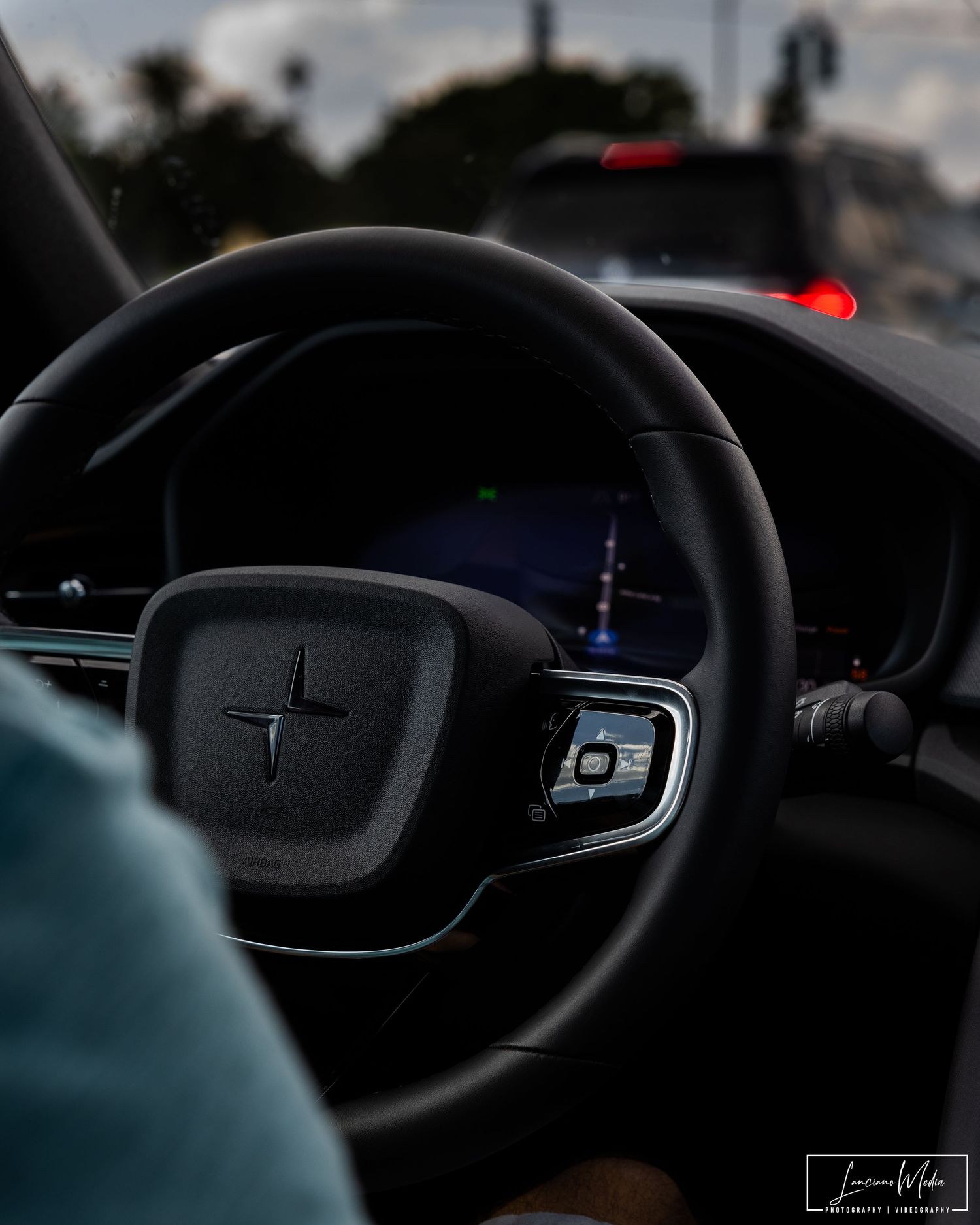 Modern car steering wheel with digital dashboard display in low light conditions.