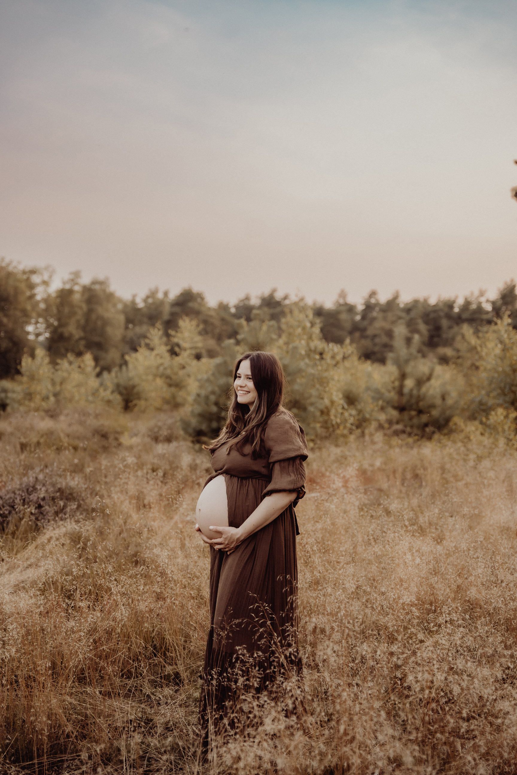 Maternity photo in brown dress amid golden autumn field.