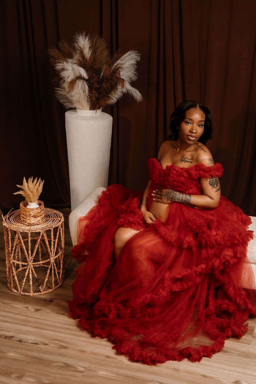 Artistic boudoir photography with a flowing red tulle dress, white vases, and natural pampas grass decorations.