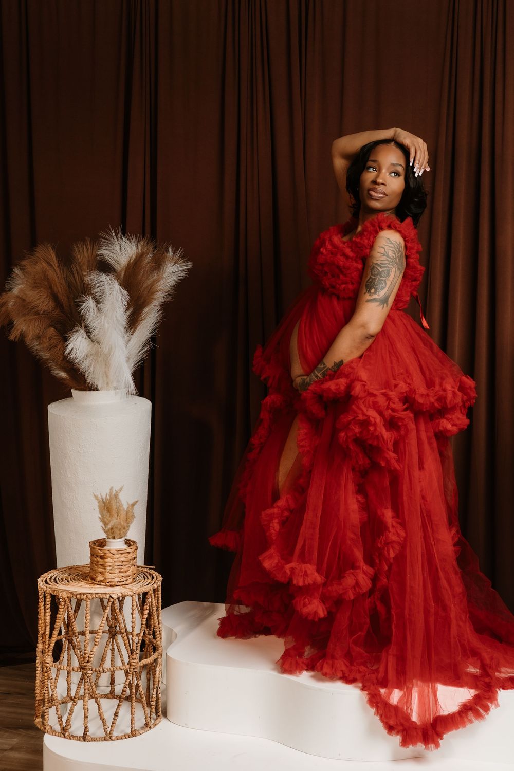 Glamorous fashion photo series featuring a flowing red tulle gown and elegant white cake display against brown curtains.