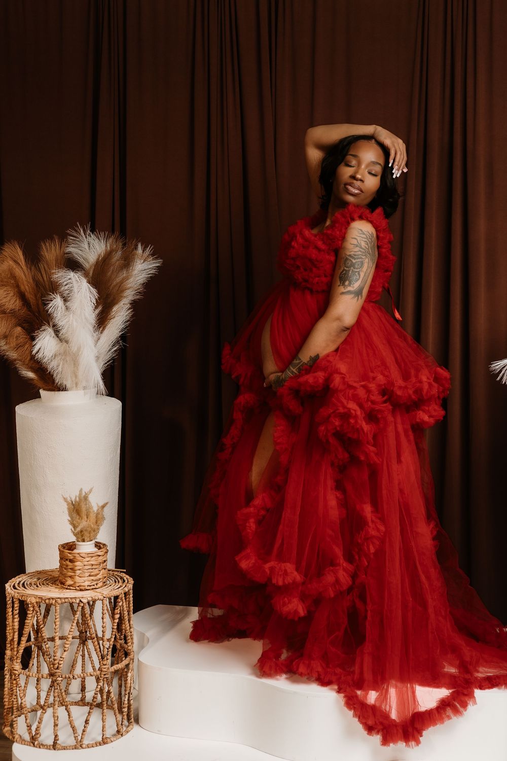 Glamorous fashion photo series featuring a flowing red tulle gown and elegant white cake display against brown curtains.