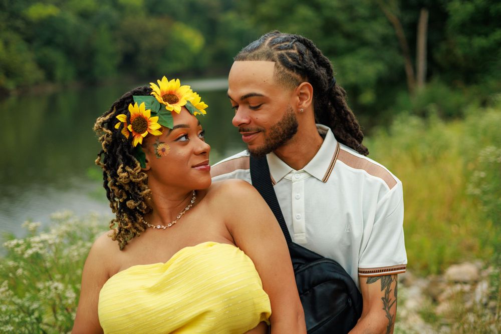 Romantic maternity photo with sunflower crown against natural lakeside setting.