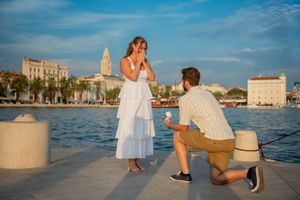 Couple sharing special moment by waterfront with Split's historic skyline in background.