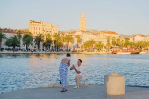 Scenic waterfront promenade in Split with historic bell tower and buildings in evening light.