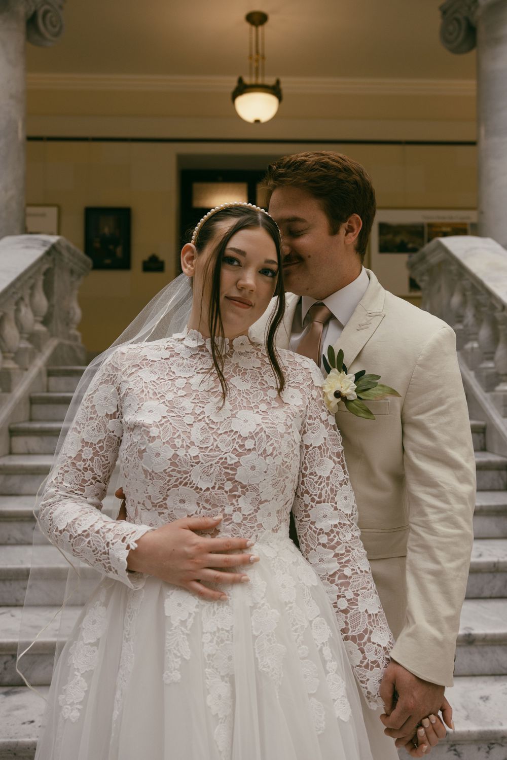 An intimate wedding portrait showcasing a detailed lace gown and classic cream suit.