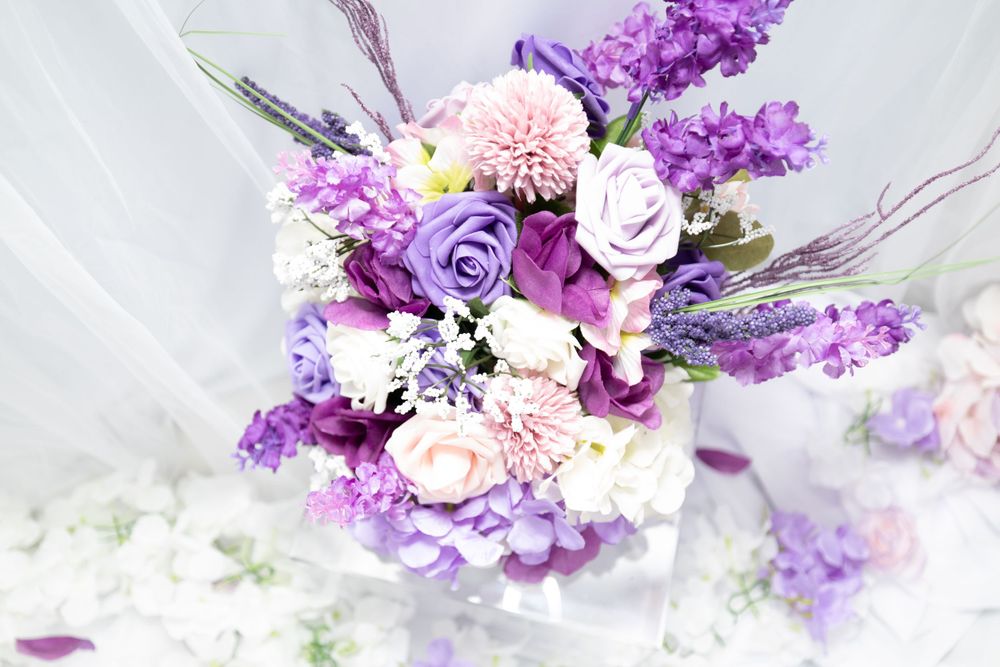 Romantic wedding bouquet with purple and pink flowers including roses and dahlias.