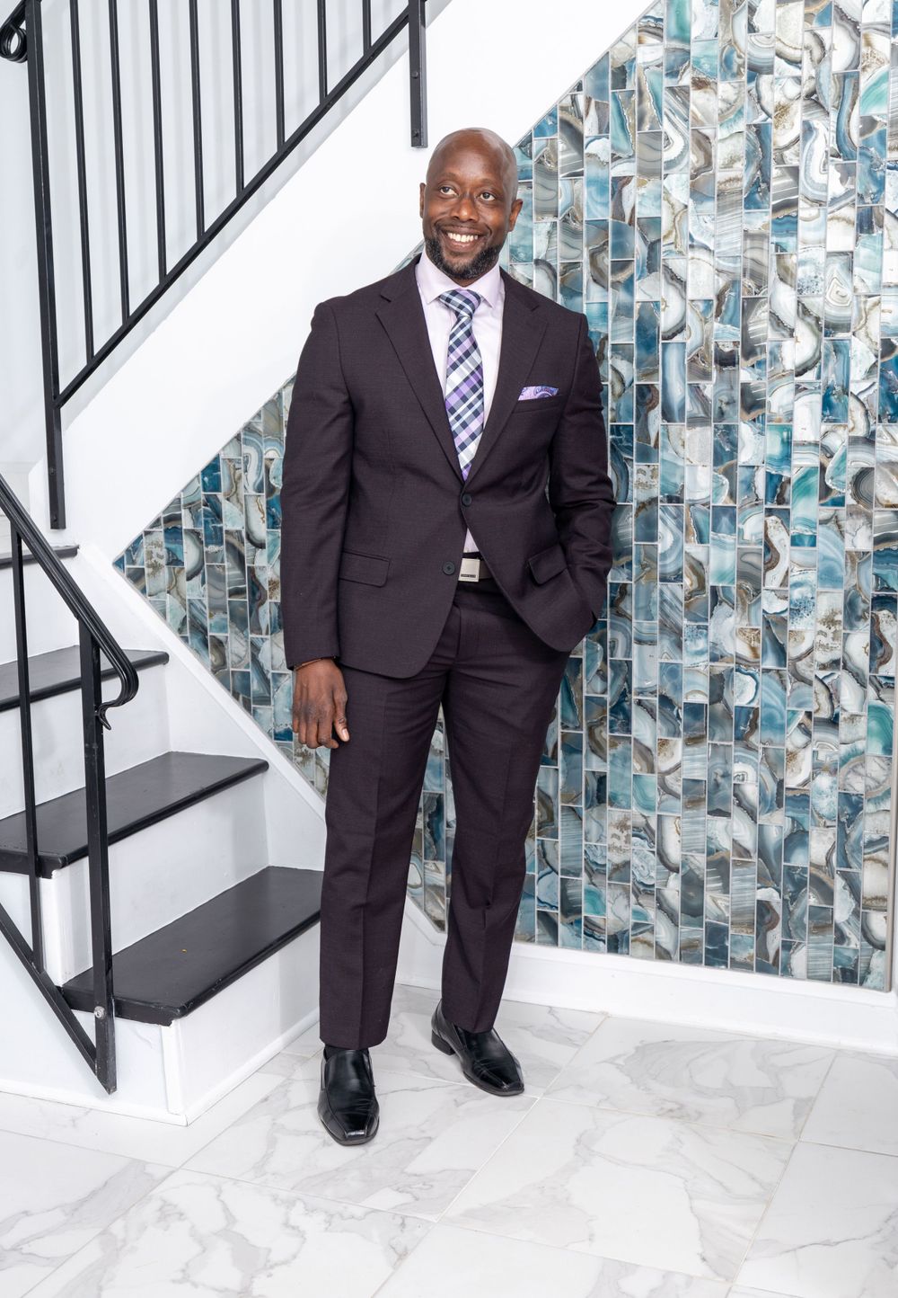 Professional portrait in modern setting with geometric wall art and staircase.