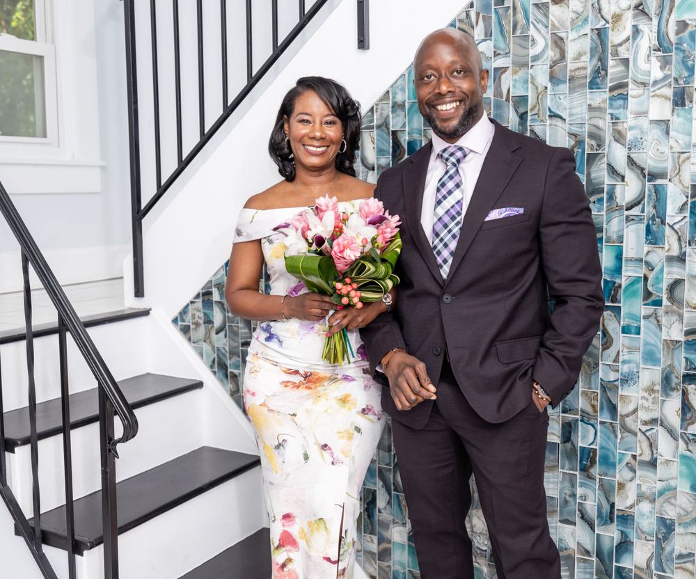 Formal portrait with decorative staircase and modern wall art backdrop.