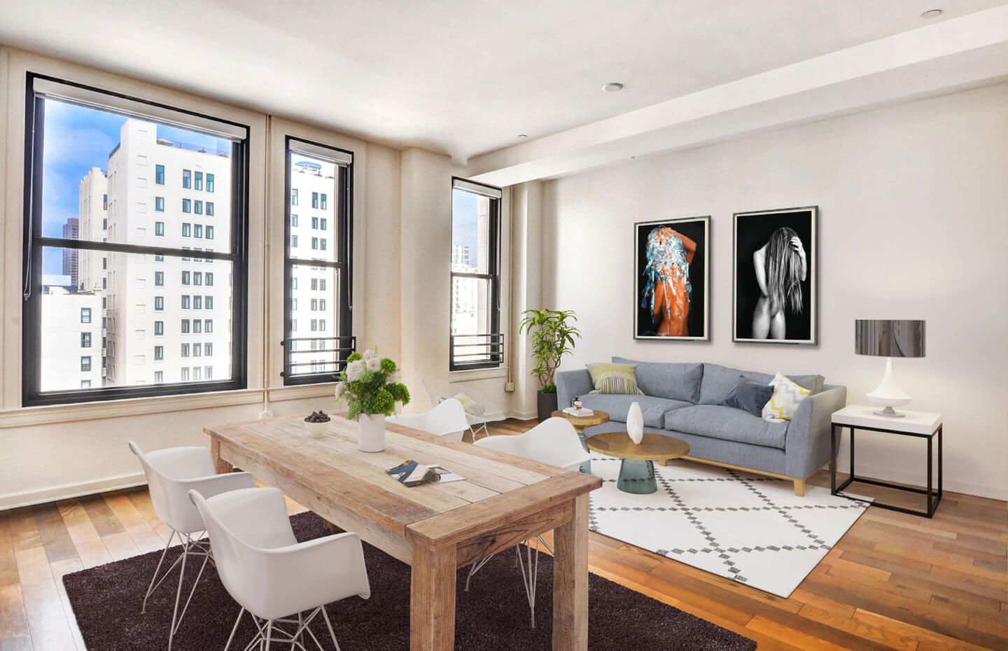 Modern apartment living space with wooden dining table, gray sofa, and large windows.