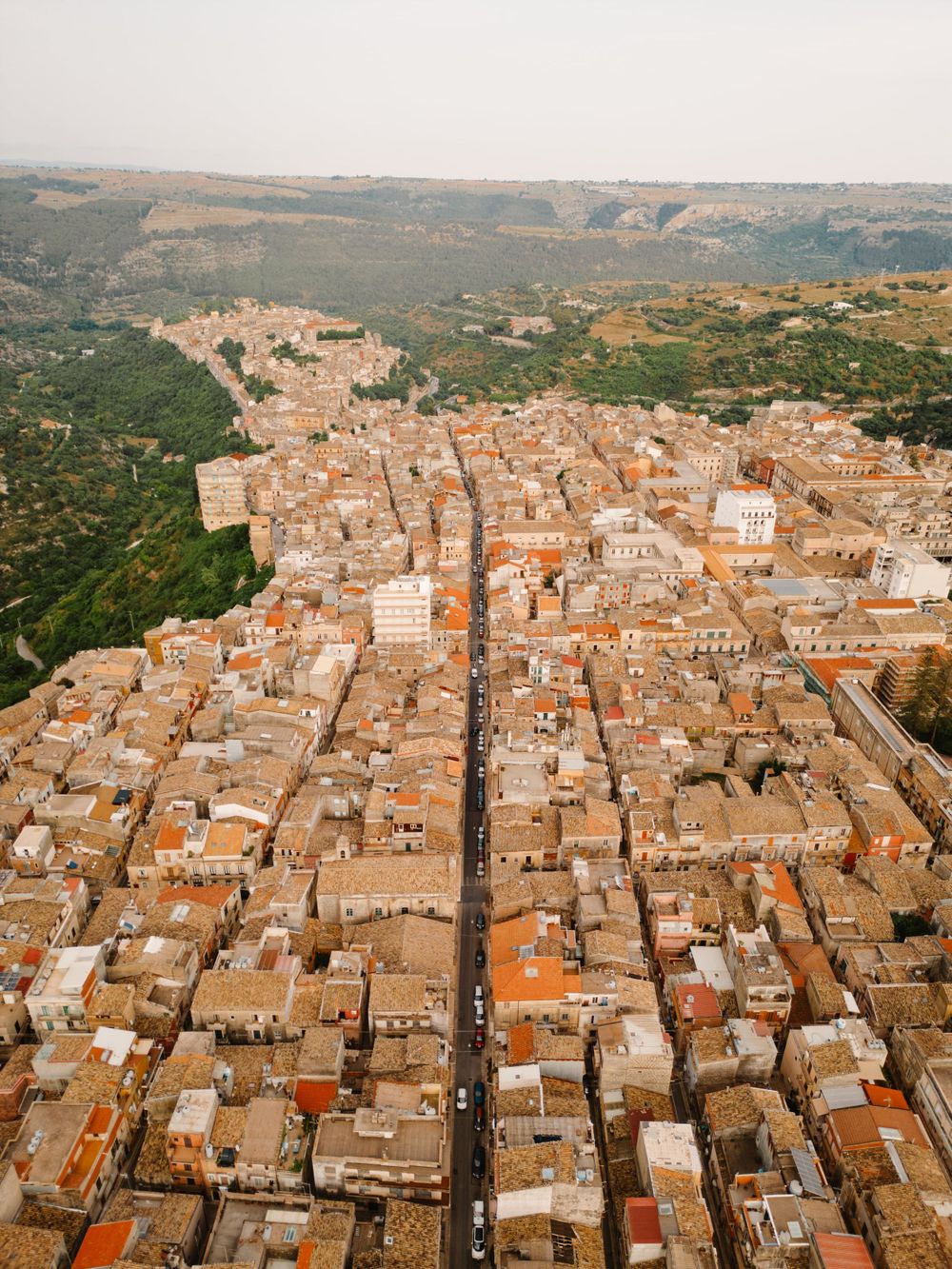 Panoramic aerial view of a historic Italian town with uniform terracotta roofs and straight streets.