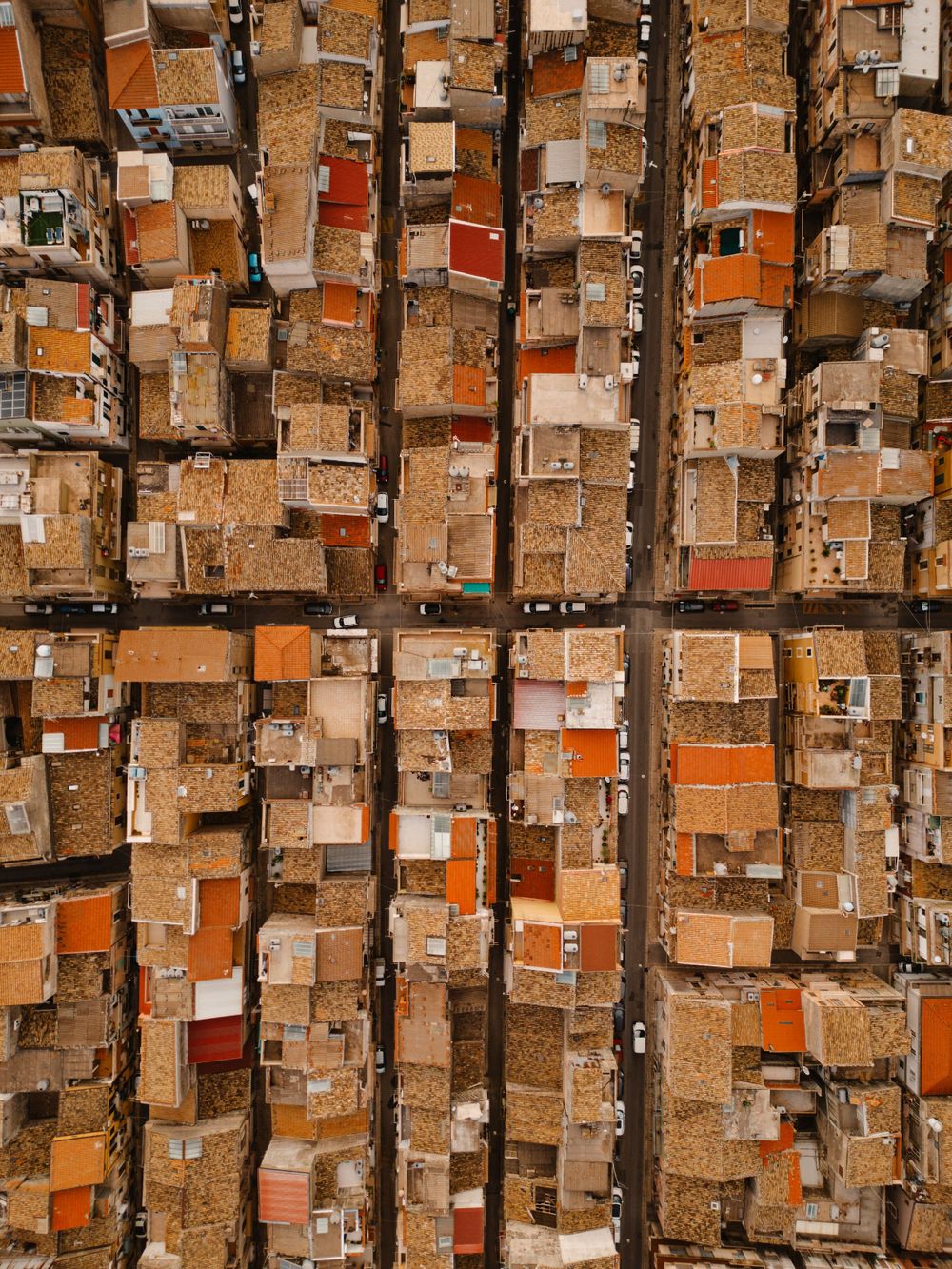 Birds-eye view of densely packed buildings with orange rooftops creating a geometric pattern.