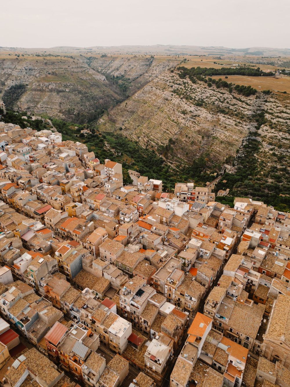 Aerial view of a Mediterranean hillside town with traditional terracotta roofs and dense urban layout.