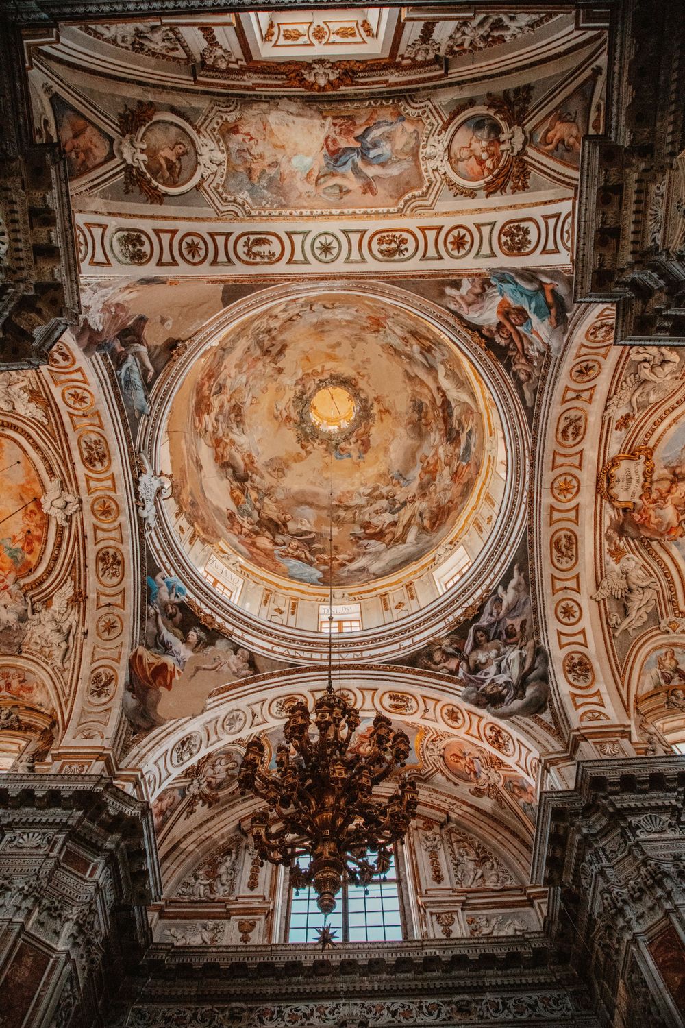 Elaborate baroque church ceiling with ornate frescoes and architectural details in gold and white.