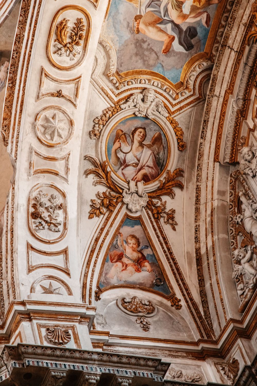 Detailed view of baroque ceiling artwork featuring religious frescoes and gilded architectural elements.