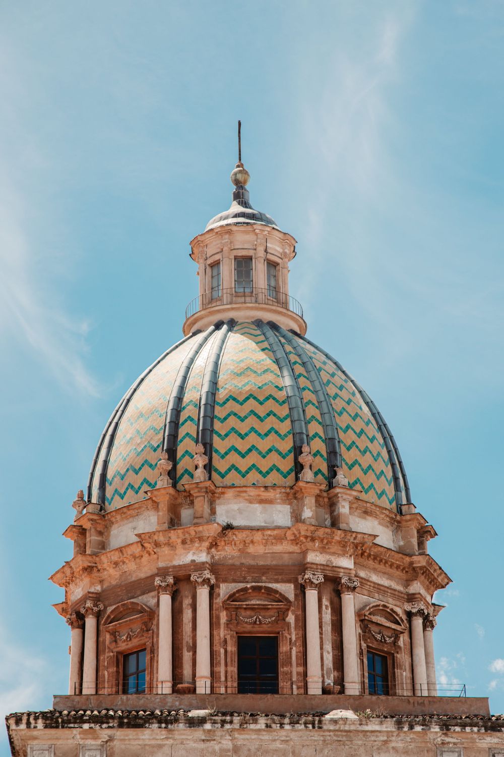 Ornate baroque dome with blue and gold geometric patterns against a bright sky.