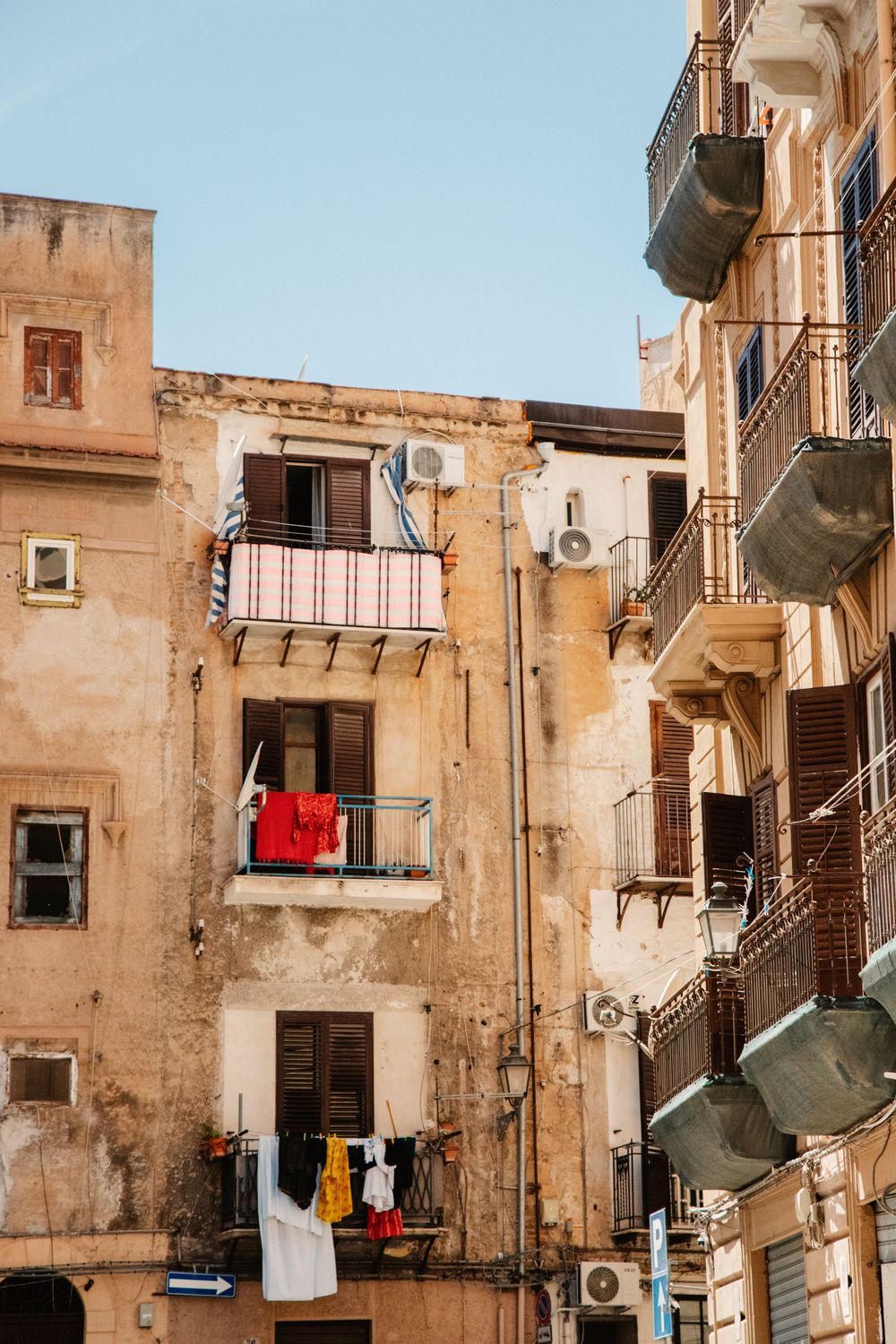 Narrow alley in an old Mediterranean neighborhood with weathered walls and hanging laundry.