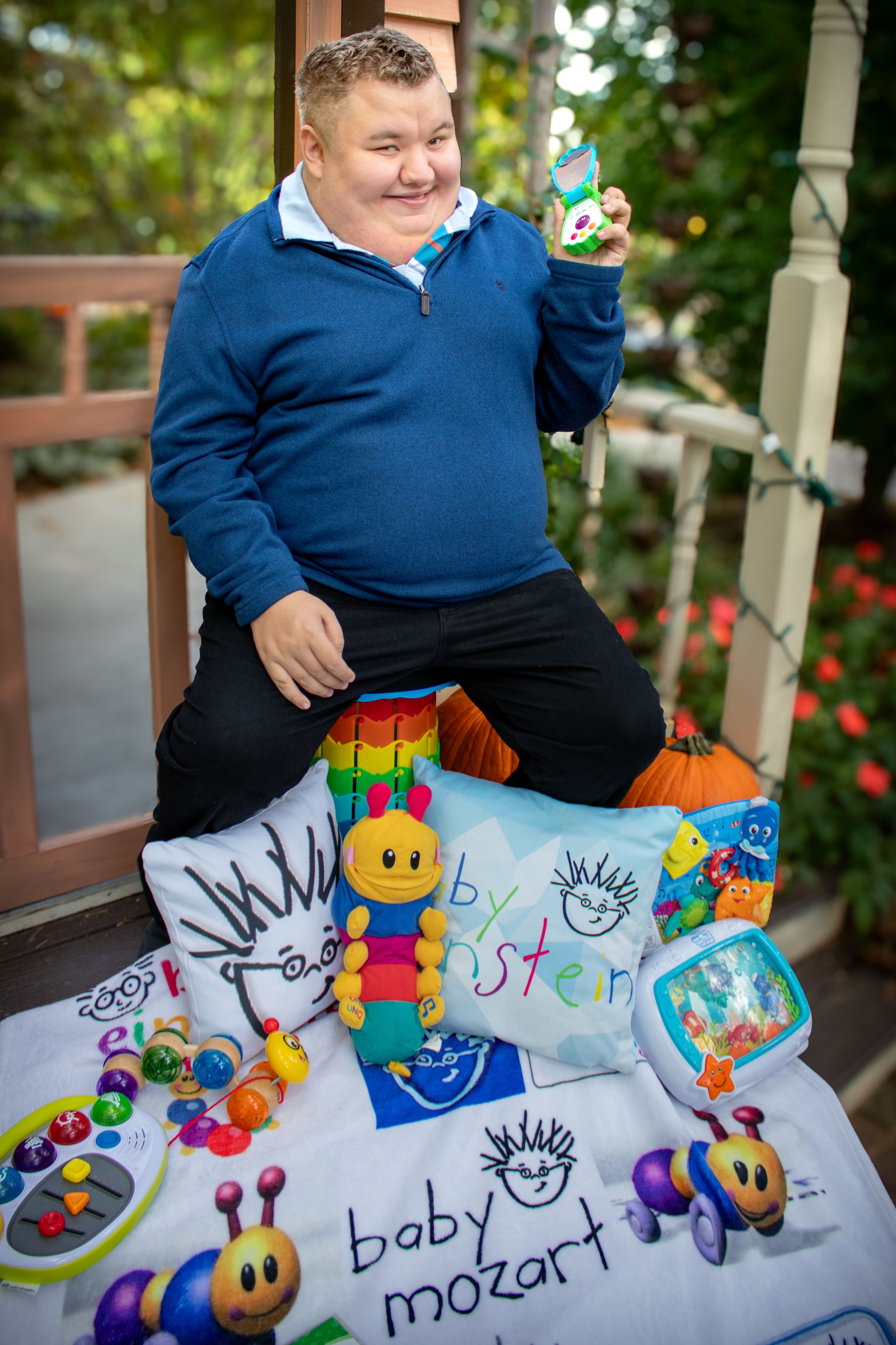 Senior portrait of a boy surrounded by his favorite toys on the porch outside in the garden smiling joyfully.